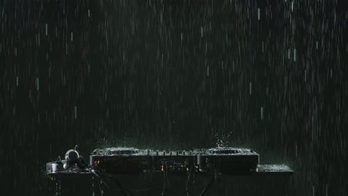 DJ Sound Control Console for Mixing Dance Music and Headphones in the Pouring Rain on the Background