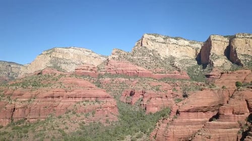 Flying over red rock landscape with green brush