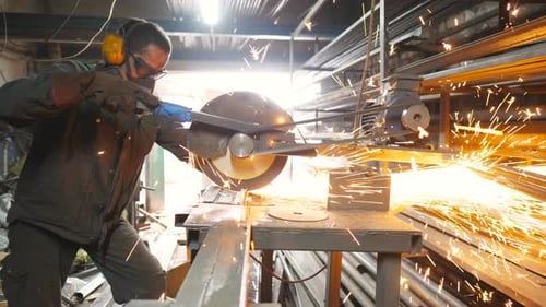 Man Using Metal Saw in Factory Workshop