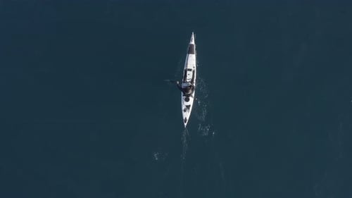 Single seat fishing canoe rowing at calm open sea water, Aerial view.
