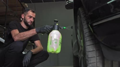 Man Cleaning Car with Spray Bottle in Garage