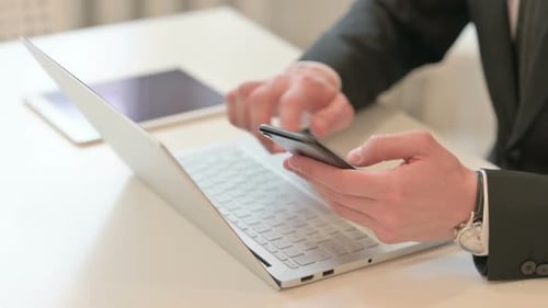 Top View of Middle Aged Businessman Using Smartphone and Laptop
