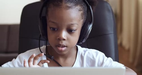 Child Wearing Headphones Using Laptop Computer