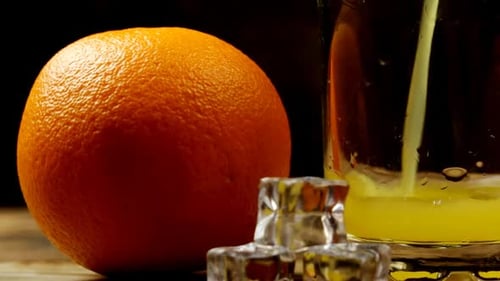 Fresh Orange, Ice And A Glass In Which Juice Is Poured On A Wooden Table