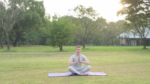 Young Handsome Man Meditating with Eyes Closed at the Park
