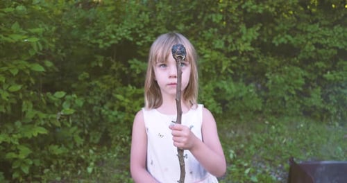 Girl Holding Burnt Marshmallow on Stick Outdoors