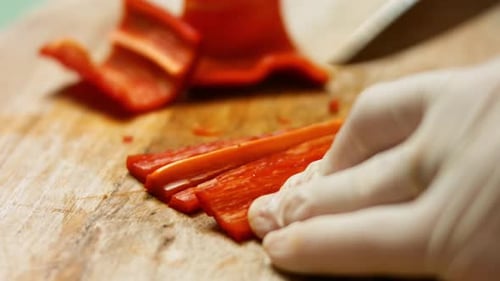 Gloved Hand Cutting a Red Bell Pepper