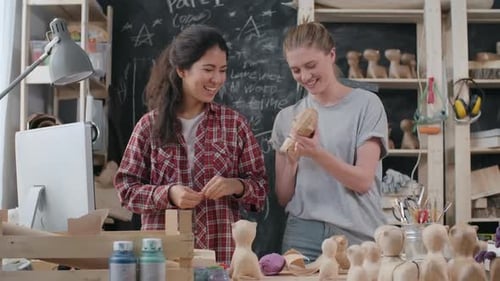 Women Crafting Wooden Figures in Bright Studio
