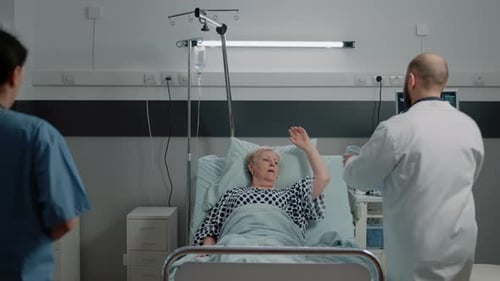 Medical Team Treating Senior Patient in Hospital Bed