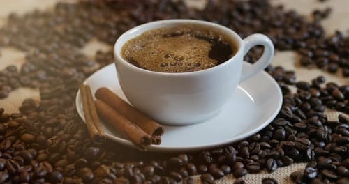 Kaffeetasse und Kaffeebohnen. Eine weiße Tasse verdampfenden Kaffees auf dem Tisch mit gerösteten Bohnen.
Aktie