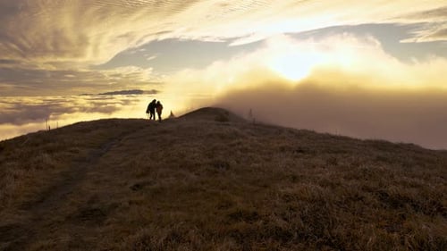 Hikers on Mountain Top Above Clouds at Sunrise