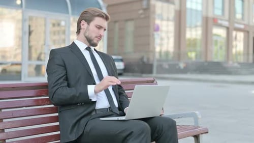 Young Businessman Working on Laptop Outdoors
