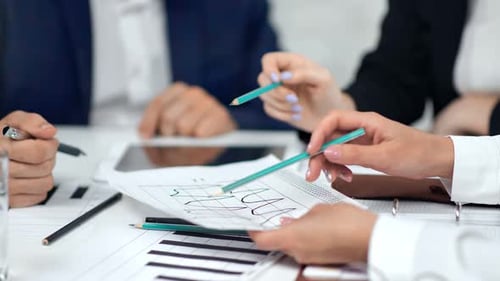 Brainstorming in Nahaufnahme von Geschäftsleuten, die einen Bleistift in der Hand halten und auf Papier zeigen, Daten, Gewinn, Grafik