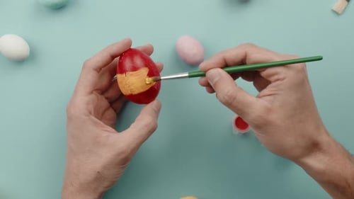 Hand of a Man is Painting Colored Easter Eggs