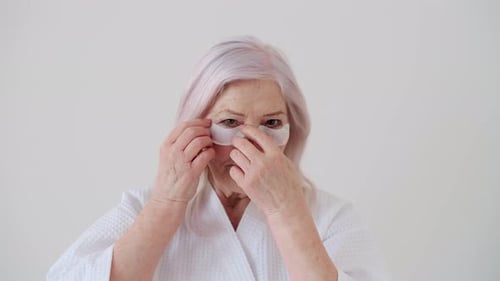 Mature Woman Applies Eye Patches for Skincare