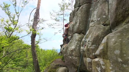 Young Man Climbing Steep Wall of Rocky Mountain