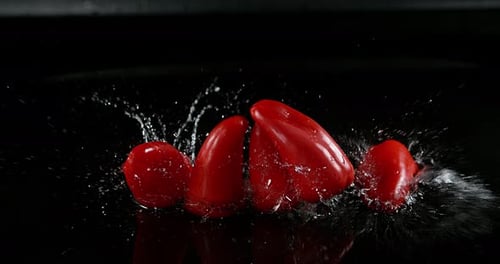 Red Sweet Peppers, capsicum annuum, Vegetable falling on Water against Black Background