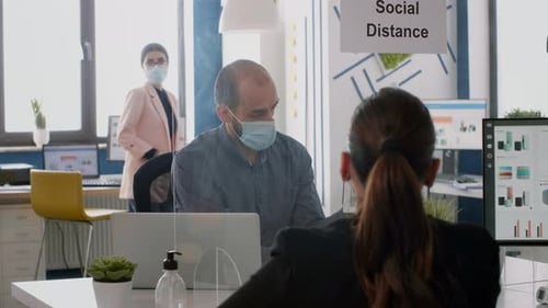 Two Collegues with Face Masks Working at Marketing Project While Sitting in Company Office
