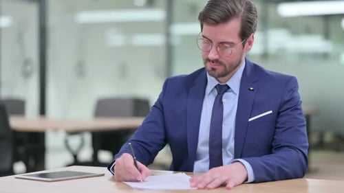 Man in Suit Signing Documents at Office