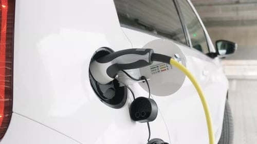 Woman Coming to Electric Car and Disconnecting Electric Vehicle From Charging Station
