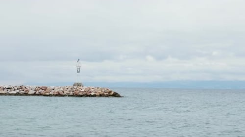 Alone Lighthouse on a Rocky Seashore and Calm Sea Water