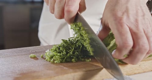 Au ralenti, un couteau de chef tranchant les feuilles de céleri
