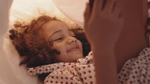 Mixed-Race Girl Using Tablet in Pillowfort