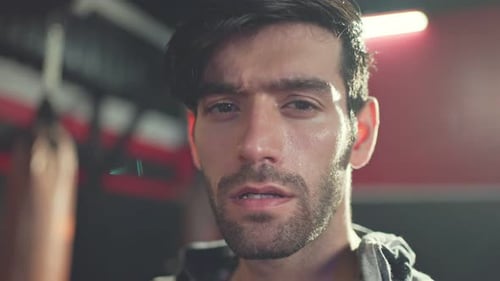 Close-up shot of Caucasian young male athlete or sportsman standing in the dark of gym stadium.