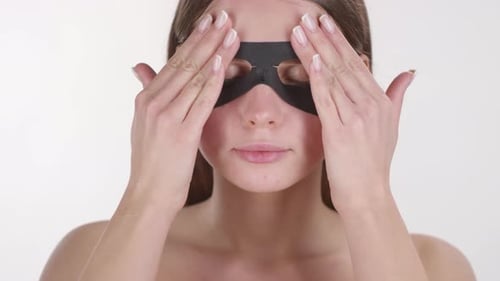 Woman Applying a Black Eye Mask to Her Face