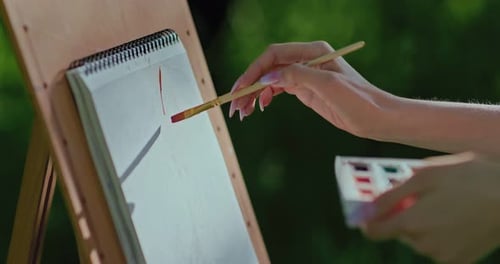 Female Hand Paints on Paper the Album Stands on an Easel