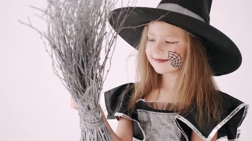 Child in Witch Costume Holding Broom Smiling