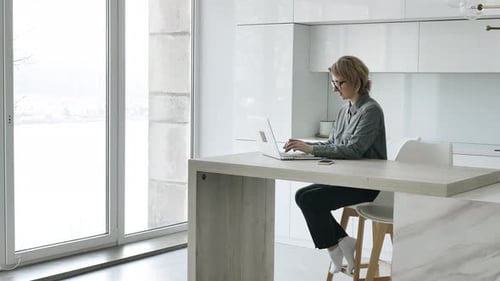 Woman Working on Laptop in Modern Urban Kitchen