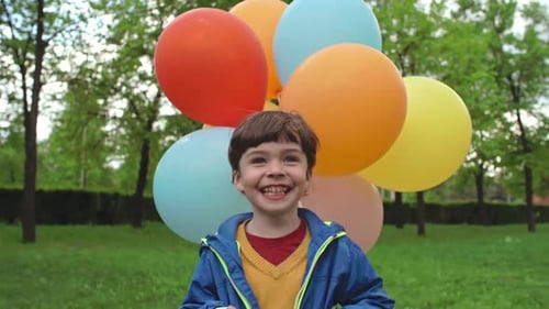 Happy Child Holds Colorful Balloons in Park