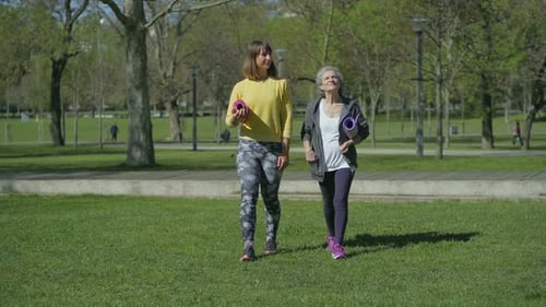 Front View of Women in Park Holding Yoga Mat in Hands, Talking