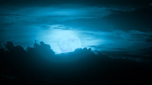 Full Moon Rising Through the Cloudy Night Sky