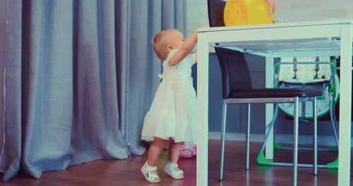 Adorable Infant Reaches for Yellow Balloon at Party