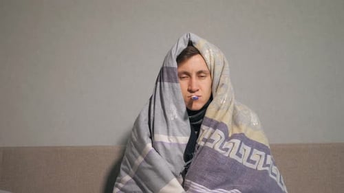 Kranker Mann in Decke misst Temperatur