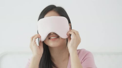 Beautiful young asian woman wearing cover eye and sleeping on bed with head on pillow comfort.