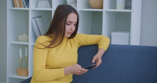 Young Woman Using Smartphone on Couch Indoors
