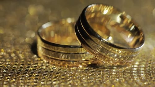 Wedding Gold Rings Lying on Shiny Glossy Surface. Shining with Light. Close-up