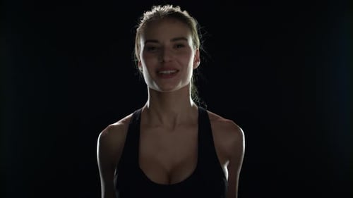 Sportfrau trainiert mit Hanteln beim Sporttraining im Dark Gym