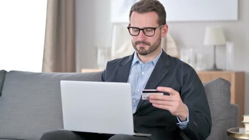 Man Using Laptop and Credit Card on Couch