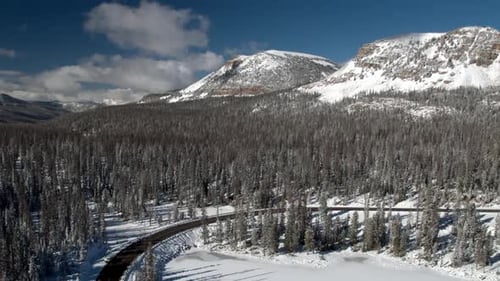 Rotating aerial view of snowy landscape over frozen forest