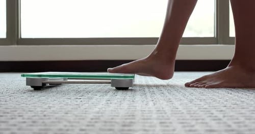 Female measuring weight on health scale