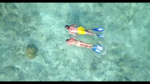 Family of two sunbathing on tranquil sea view beach trip by blue ocean with white sand background of