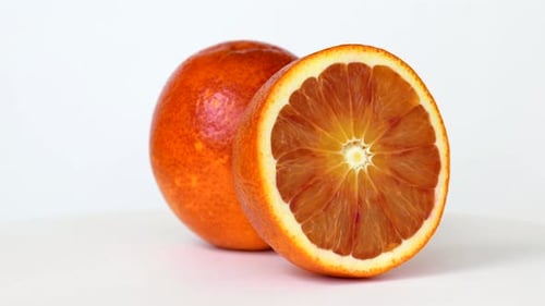 Sangre media naranja y entera girando sobre fondo blanco