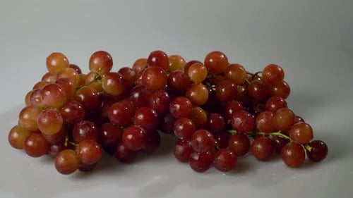 A bunch of red seedless grapes on a white surface