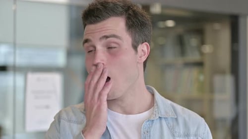 Portrait of Sleepy Young Male Designer Yawning in Office