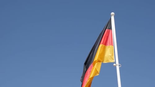 German Flag Waving in the Wind Against Blue Sky