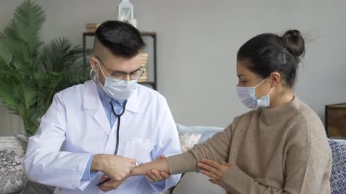 Doctor Listens to Patient Pulse During Home Visit